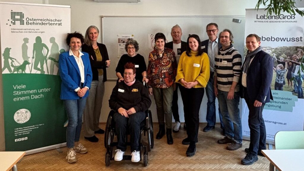 Gruppenbild stehender Personen, ganz vorne eine Person im Rollstuhl